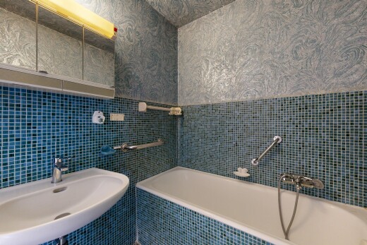 bathroom featuring a bath, tile walls, and wallpapered walls