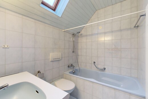 bathroom with a skylight, vaulted ceiling, tile walls, tiled shower / bath, and vanity