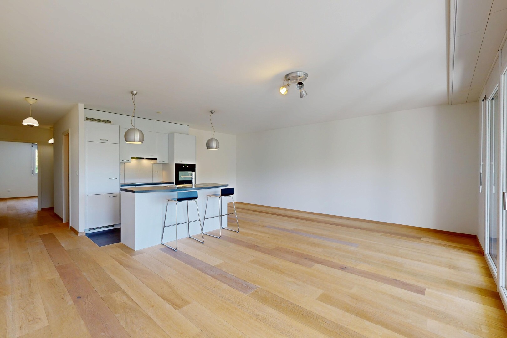 cuisine avec ouvert sur l'espace de vie, bar de cuisine, sol en finition bois, wood finish floor, et armoires blanches