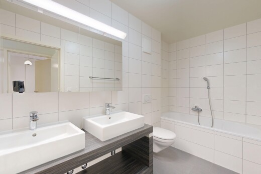 full bath featuring tile walls, a garden tub, tasteful backsplash, and double vanity