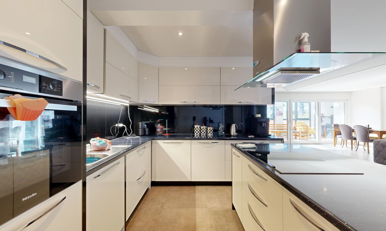 cuisine avec hotte, dark countertops, four, inside property, et armoires à panneau plat