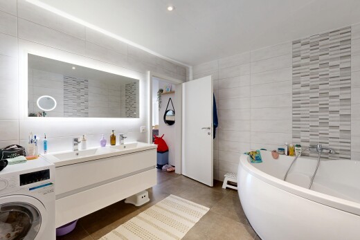 salle de bains avec mur en carrelage, tile wall, bain, double vasque, et lave-linge et sèche-linge