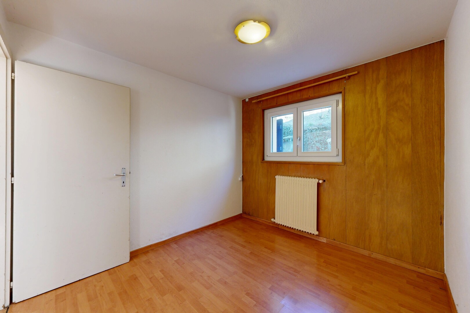pièce vide avec radiateur, inside property, sol en finition bois, wood finish floor, et lumière naturelle