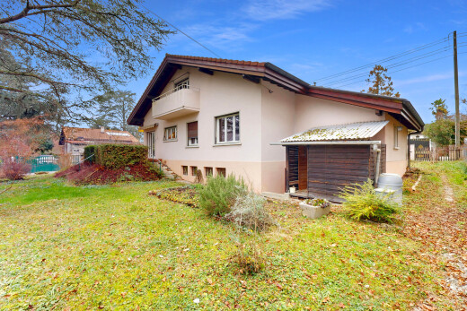 façade avec clôture, bardage en stuc, power lines view, property visible, et pelouse
