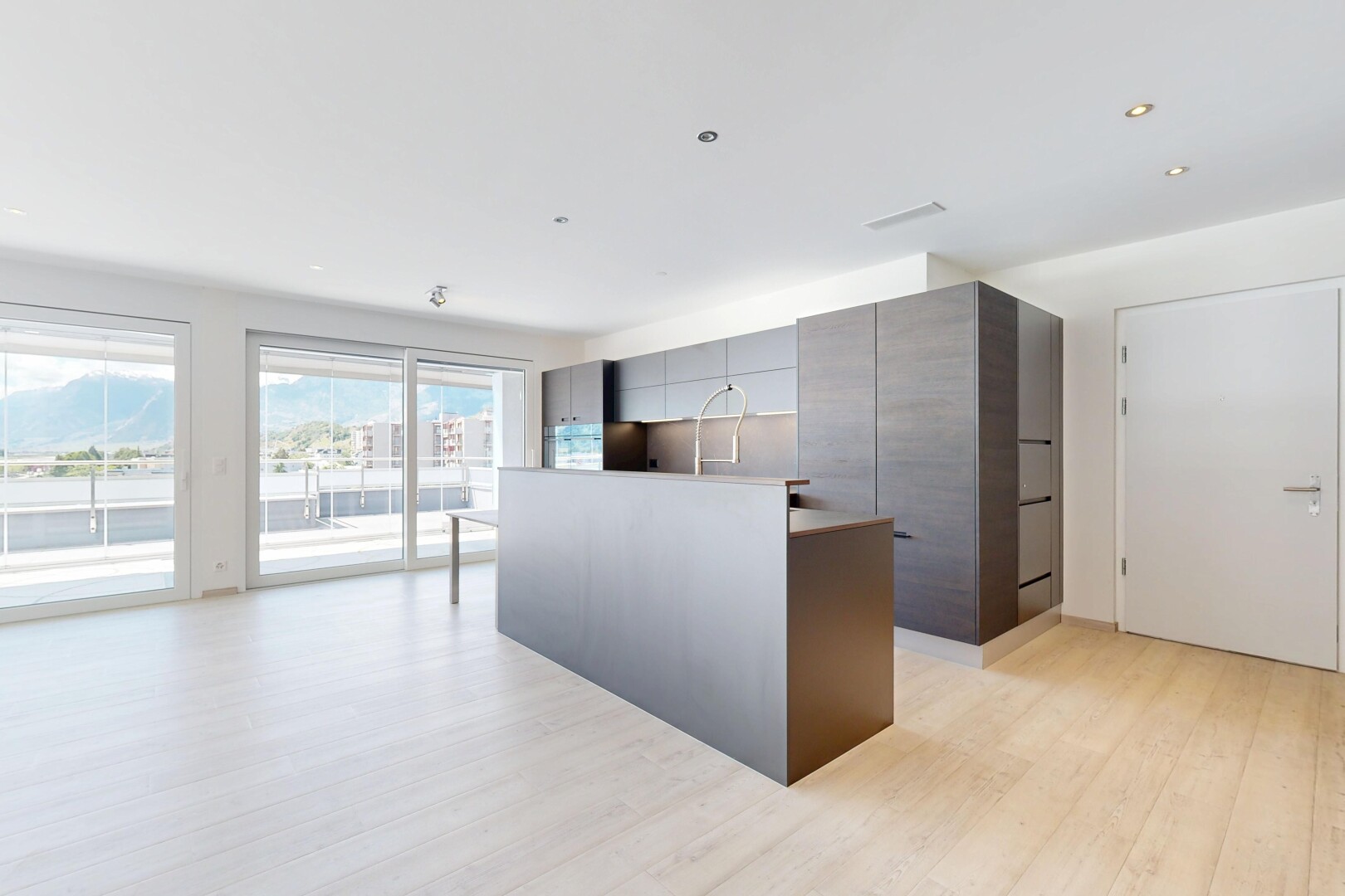 cuisine avec two heights countertops, light floor, sol en finition bois, wood finish floor, et armoires à panneau plat