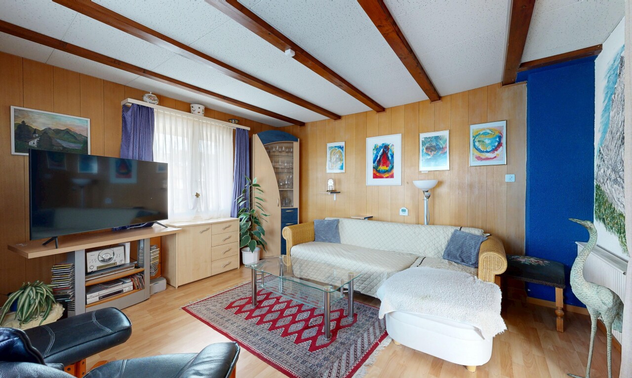 living area with wooden walls, beamed ceiling, and wood finished floors