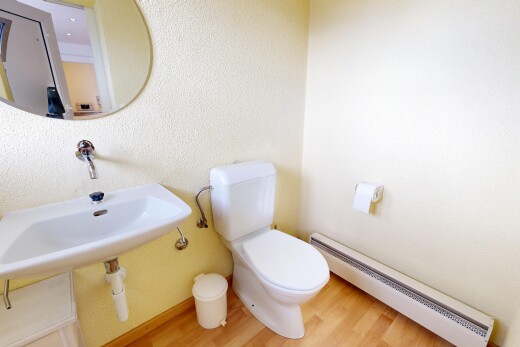 salle de bains avec radiateur à plinthe, toilette, miroir, inside property, et sol en finition bois
