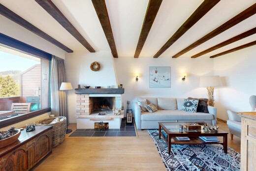 living area featuring light wood-type flooring, beamed ceiling, and a fireplace