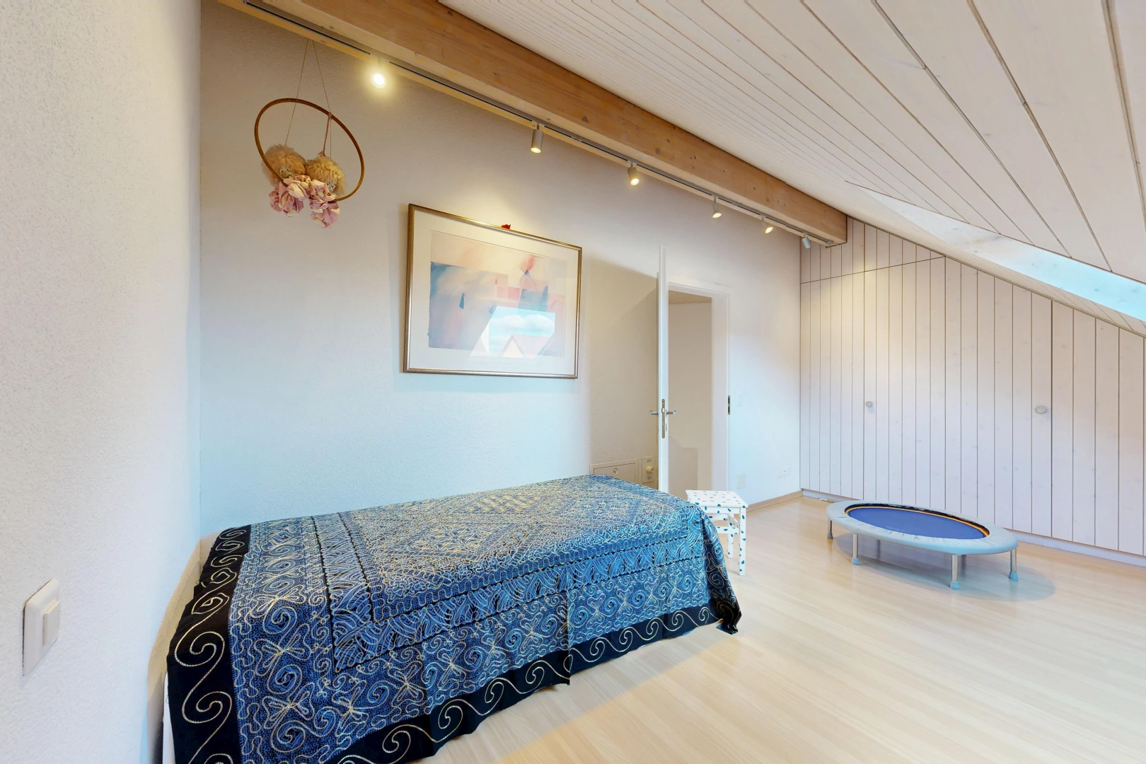 room / bedroom with light wood finished floors, wood walls, and track lighting