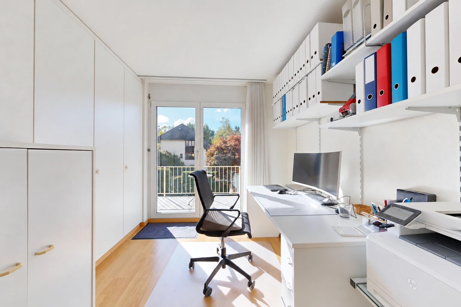 home office with built in study area, light wood-style floors, and built in shelves