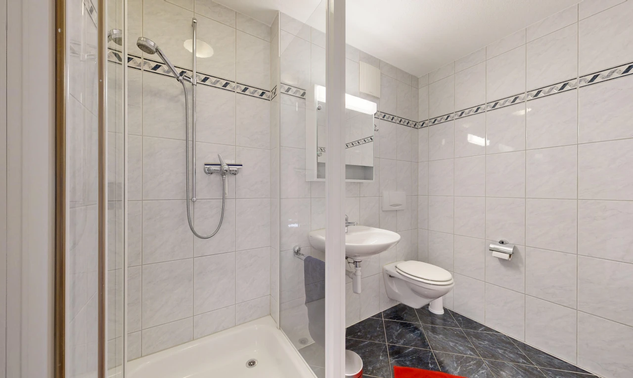 bathroom with a shower stall and tile walls