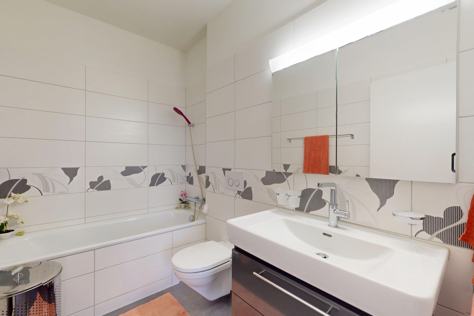 salle de bains avec toilette, mur en carrelage, salle de bain complète, miroir, et lavabo (ou coiffeuse selon le contexte)