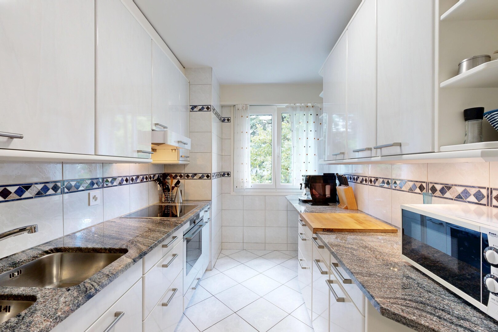 cuisine avec plans de travail en pierre, stone countertops, micro-ondes, armoires blanches, et white cabinets