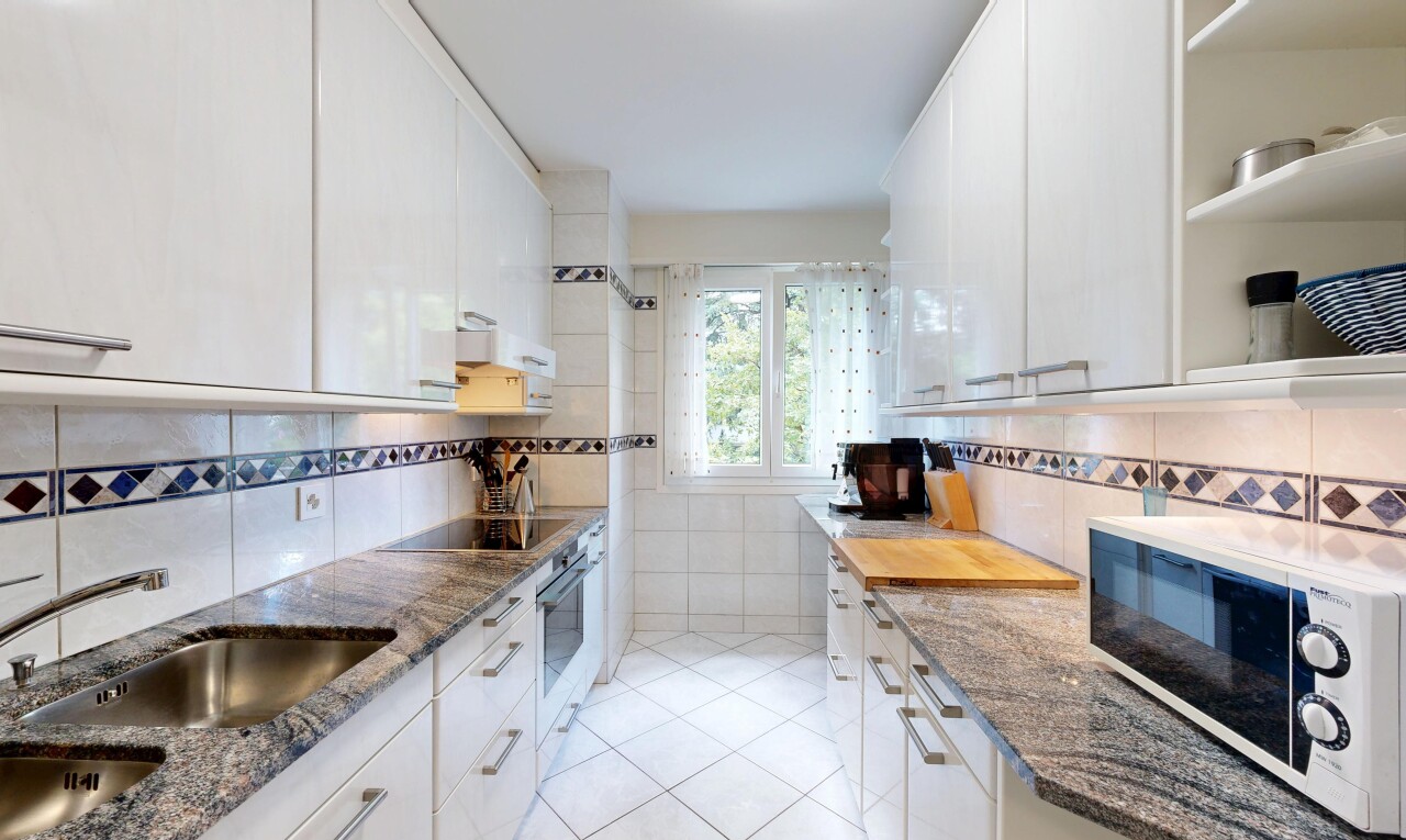 cuisine avec plans de travail en pierre, stone countertops, micro-ondes, armoires blanches, et white cabinets