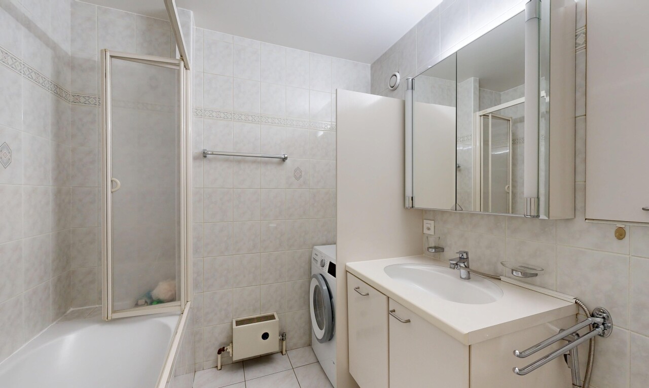 salle de bains avec mur en carrelage, tile wall, miroir, lavabo (ou coiffeuse selon le contexte), et salle de bain complète