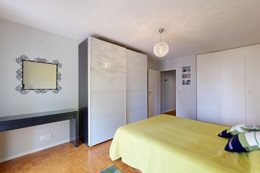 chambre avec cloison sèche, drywall, deux placards, sol en finition bois, et wood finish floor