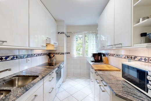 cuisine avec plans de travail en pierre, stone countertops, micro-ondes, armoires blanches, et white cabinets