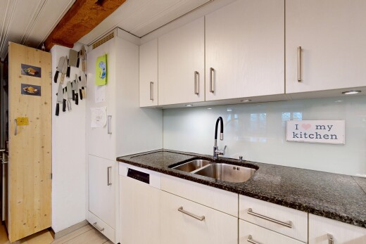 cuisine avec inside property, évier, plans de travail en pierre, et armoires blanches