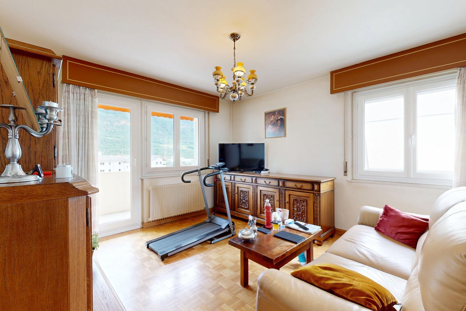 living area featuring parquet floors, suspended lighting, and radiator