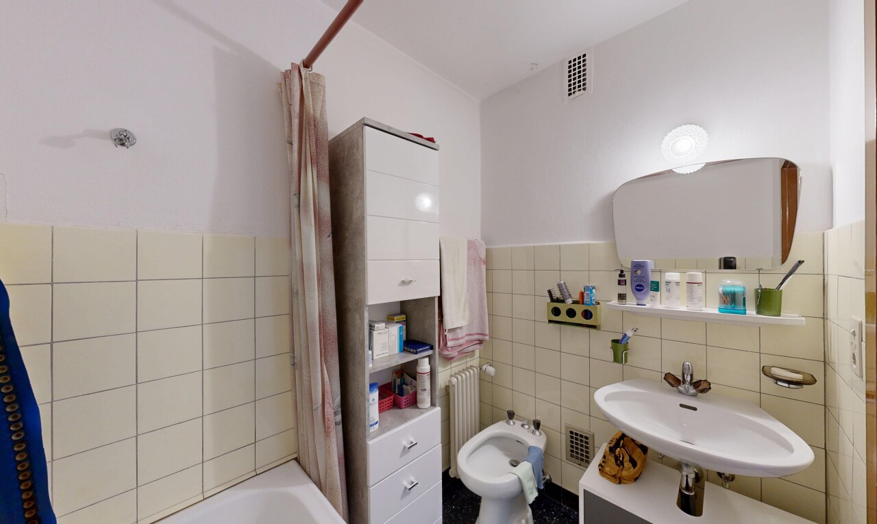 full bath featuring tile walls, a bidet, shower / bath combination with curtain, a wainscoted wall, and radiator