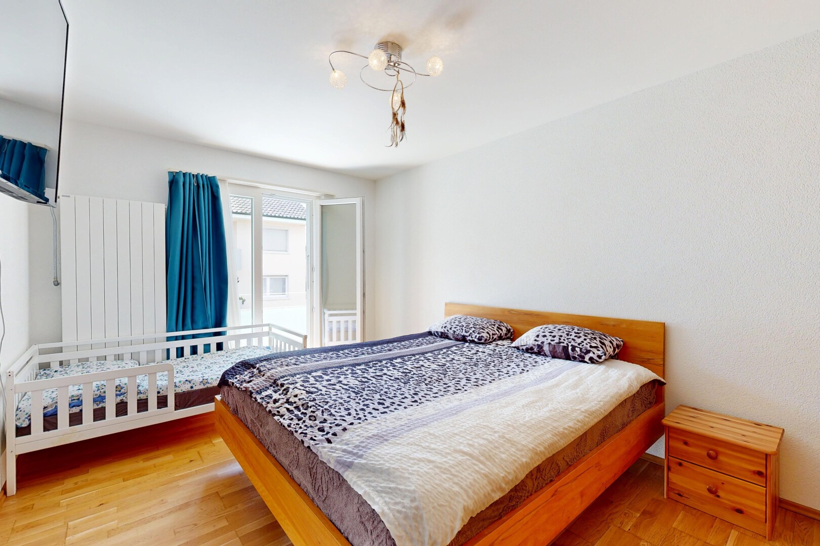 zimmer / schlafzimmer mit fernseher, holzfußboden, wood finish floor, inside property, und natürliches licht