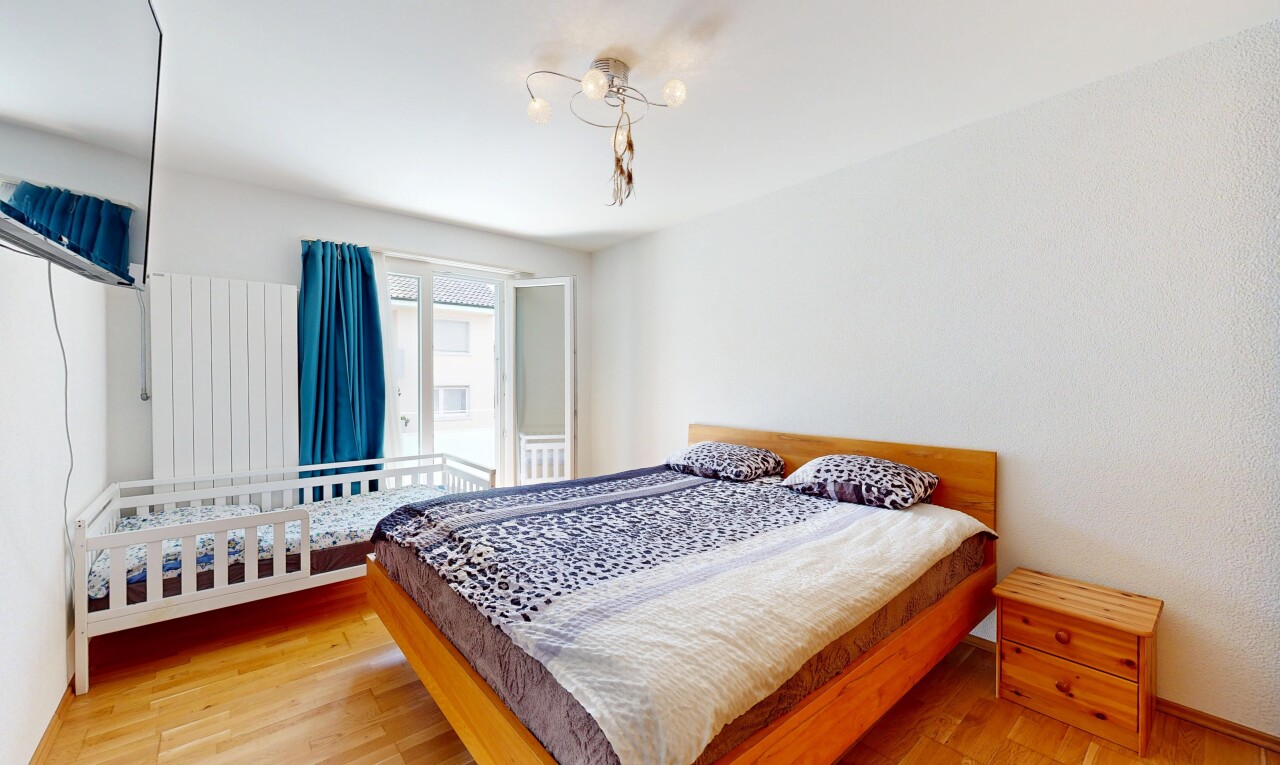 zimmer / schlafzimmer mit fernseher, holzfußboden, wood finish floor, inside property, und natürliches licht