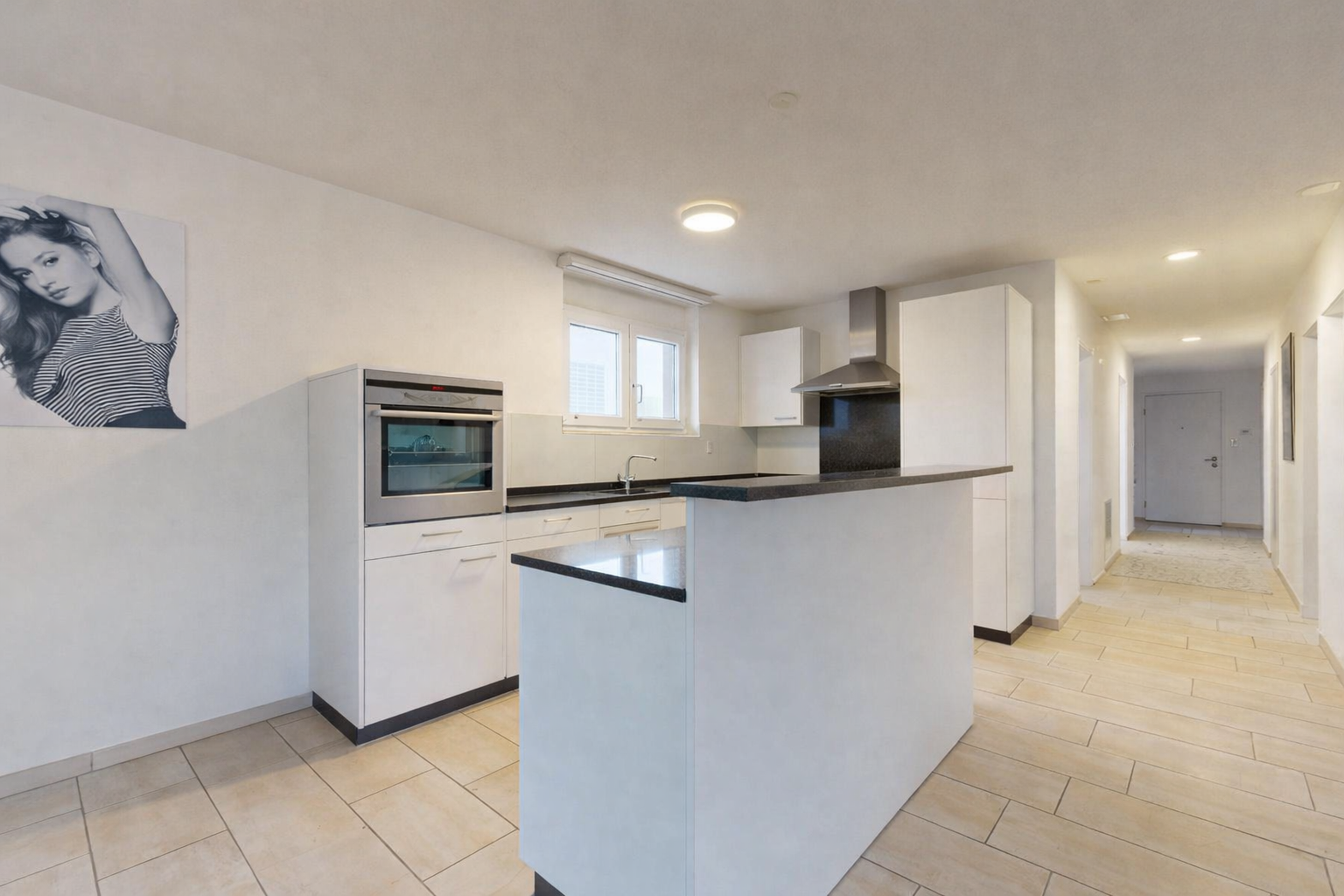 kitchen featuring oven, white cabinetry, wall chimney range hood, dark countertops, and a center island