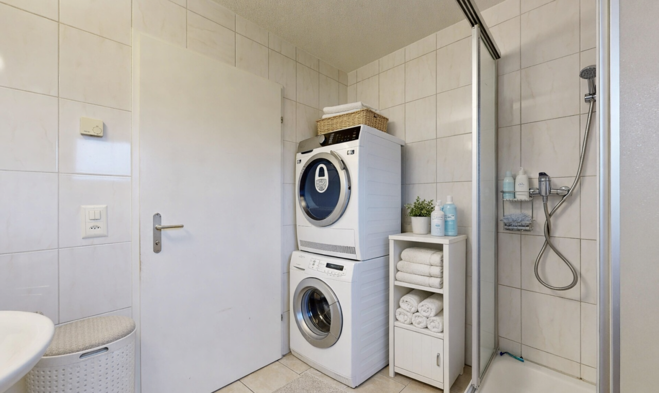 washroom featuring tile walls, light tile patterned floors, and stacked washing machine and dryer