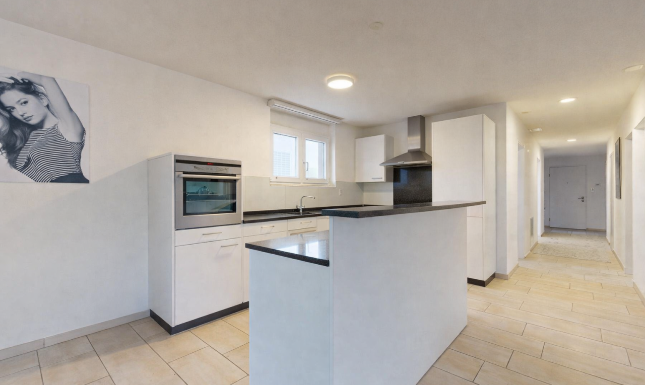 kitchen featuring oven, white cabinetry, wall chimney range hood, dark countertops, and a center island