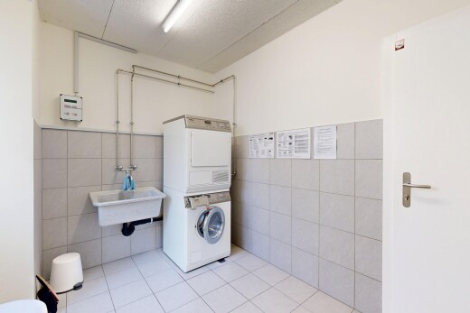 buanderie avec tile wall, lave-linge et sèche-linge superposés, drywall, inside community, et tile floor