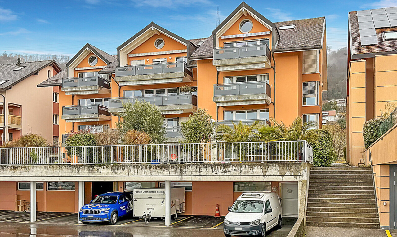 view of building exterior with stairs and uncovered parking