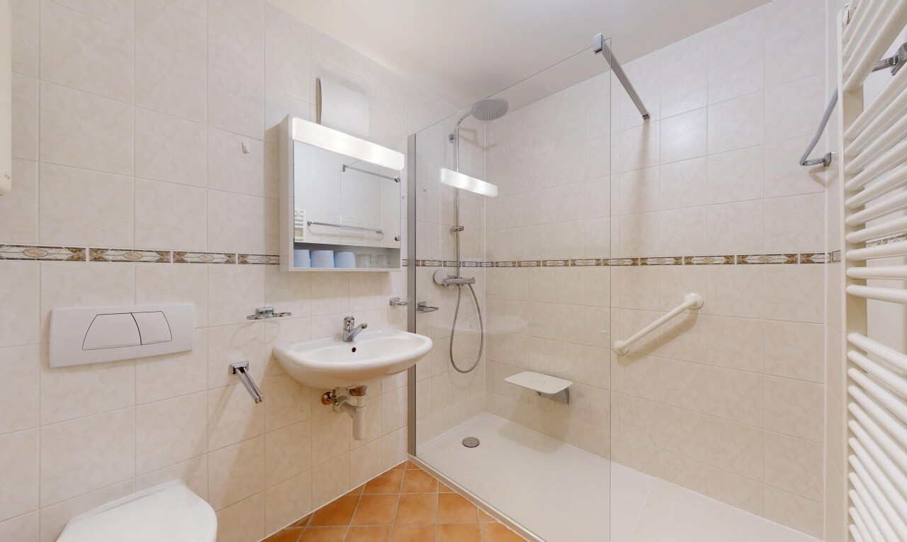 full bathroom featuring a towel warming rack, tile walls, walk in shower, radiator heating unit, and tile patterned flooring