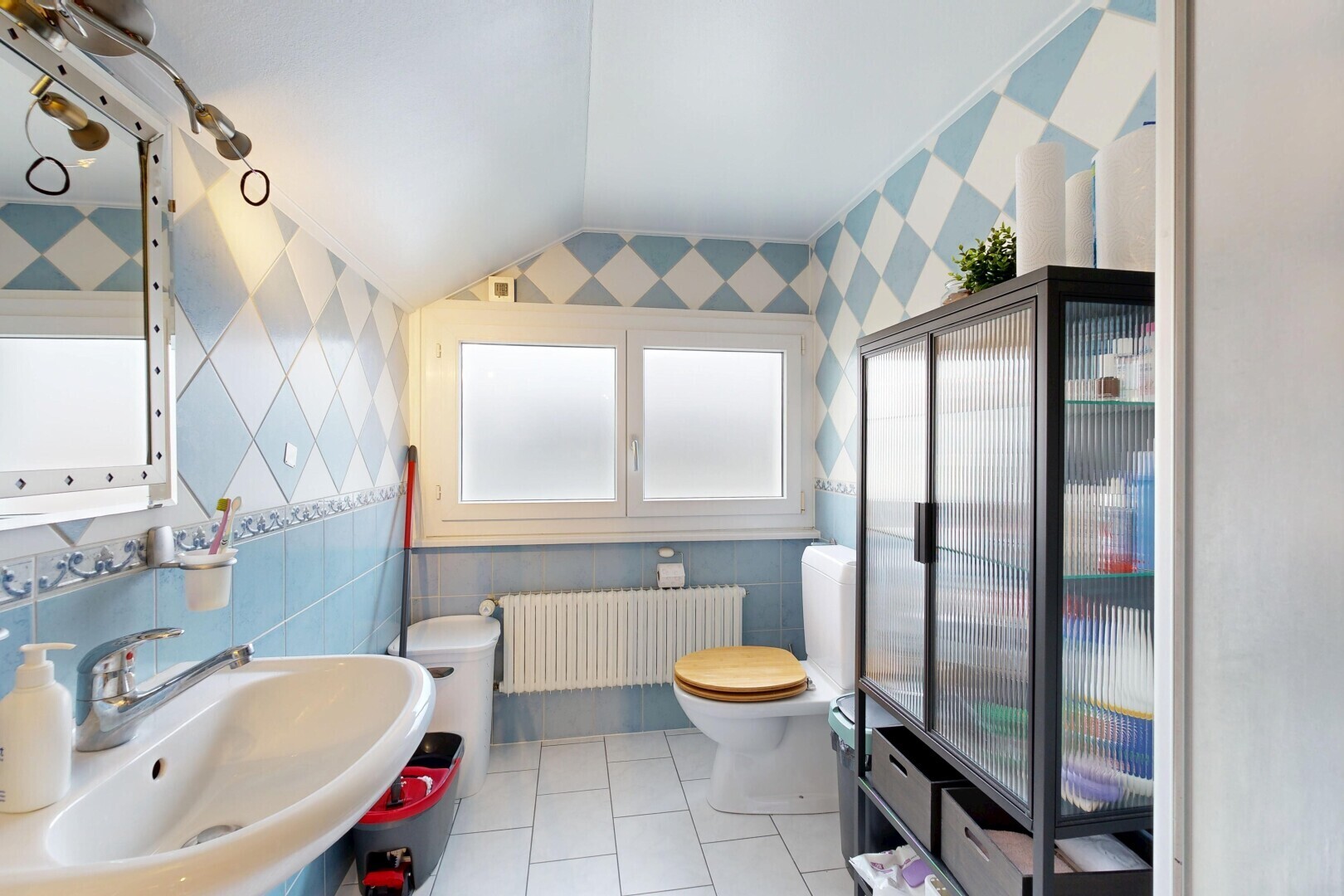 salle de bains avec toilette, évier, radiateur, vaulted ceiling, et plafond voûté