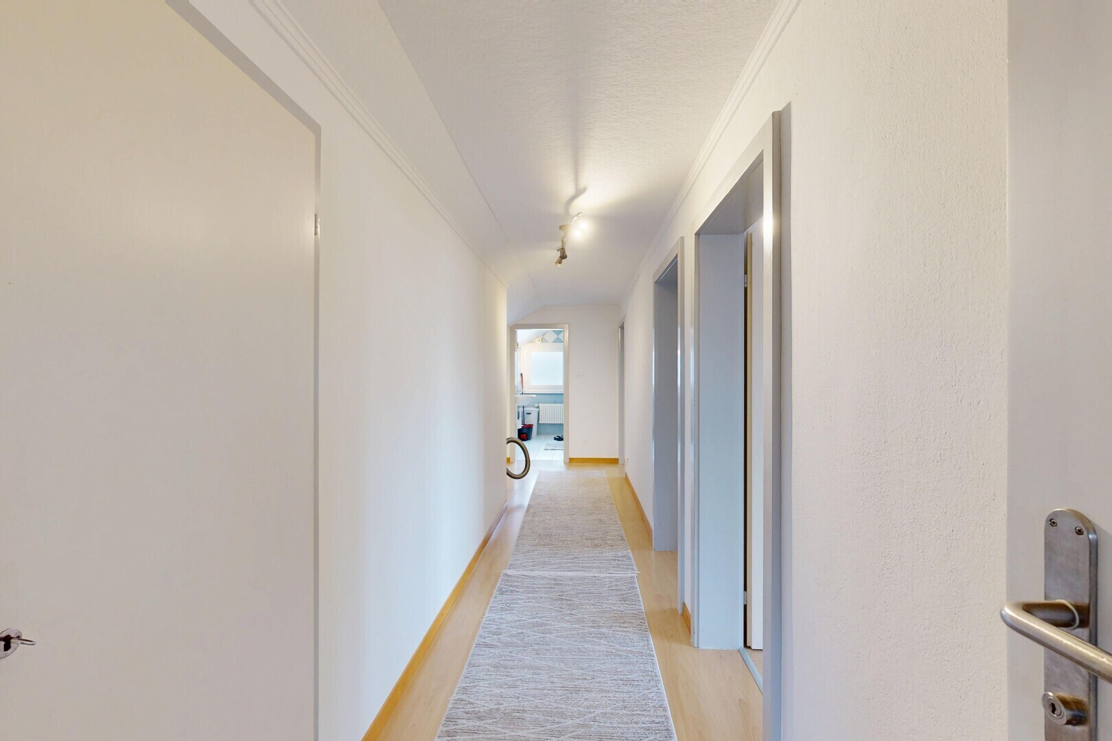 couloir avec inside property, light floor, wood finish floor, sol en finition bois, et drywall