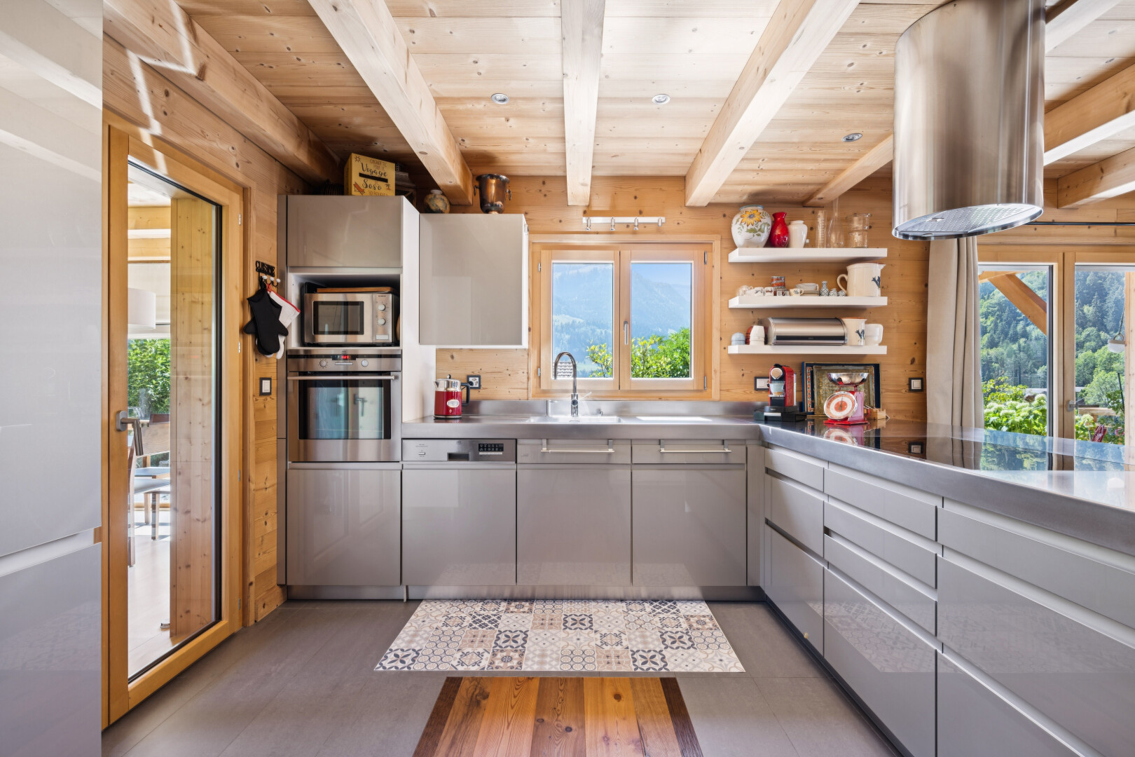 kitchen featuring stainless steel counters, open shelves, gray cabinetry, a wooden ceiling with exposed beams, and stainless steel appliances