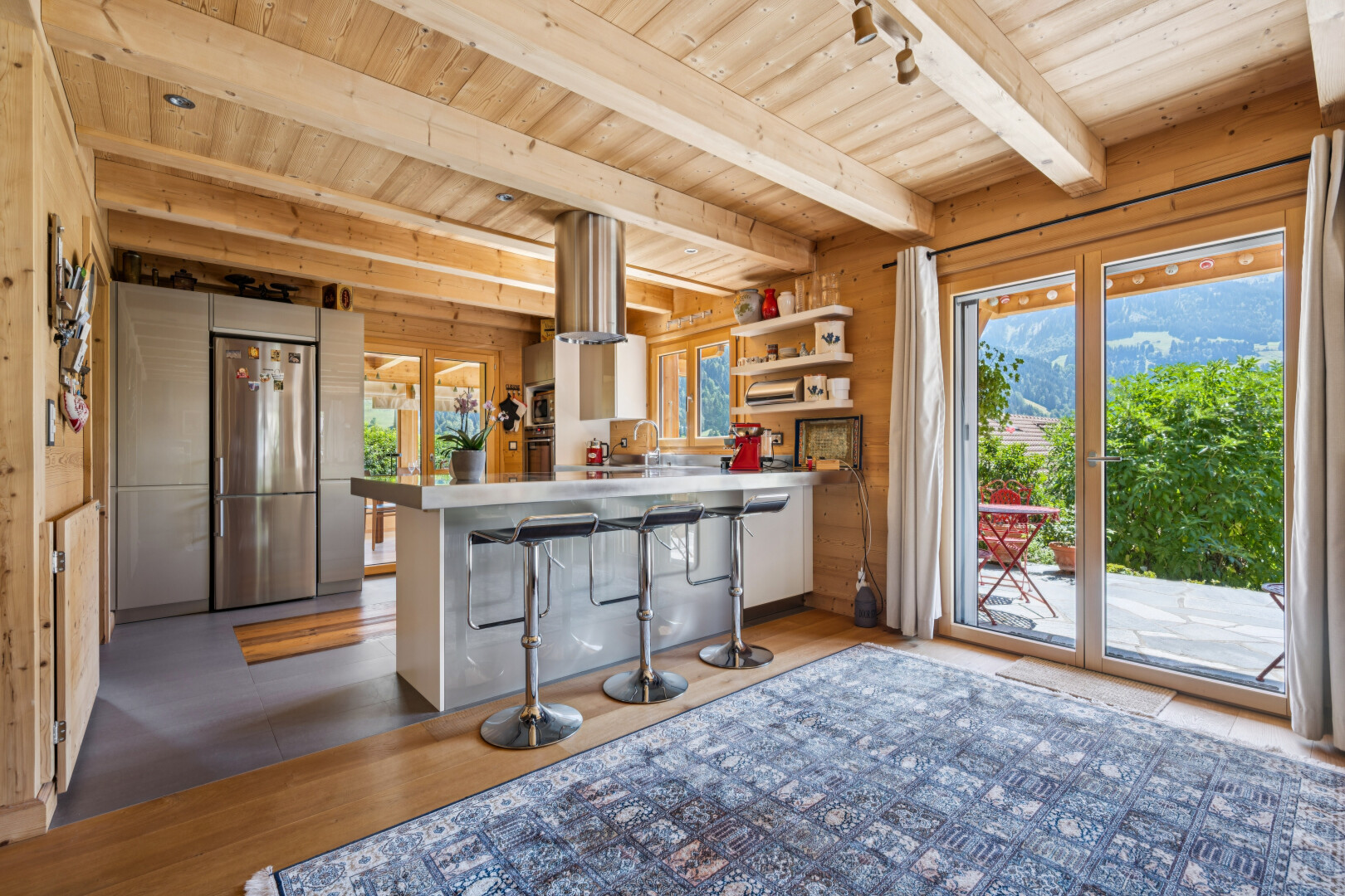 kitchen featuring a wood ceiling with exposed beams, stainless steel refrigerator, a breakfast bar, a peninsula, and open shelves