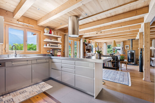 kitchen with stainless steel counters, a wood ceiling with exposed beams, a wood stove, a peninsula, and open shelves
