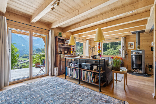 living room with a wood stove, light wood-style flooring, a mountain view, a wood ceiling with exposed beams, and wood walls