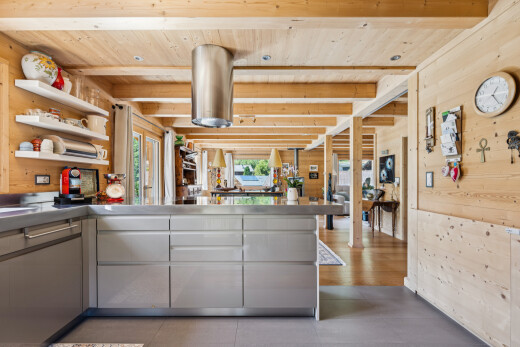 kitchen featuring stainless steel counters, wooden walls, a wooden ceiling with exposed beams, a peninsula, and open shelves