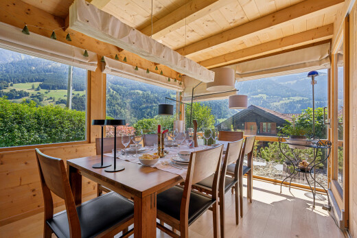 dining room featuring a wood ceiling with exposed beams, light wood finished floors, wooden walls, and a mountain view