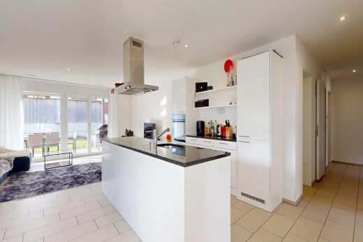 cuisine avec armoires blanches, white cabinets, hotte, dark countertops, et light floor