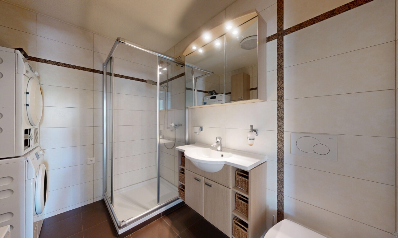 full bath with a stall shower, tile walls, vanity, stacked washing machine and dryer, and dark tile patterned floors