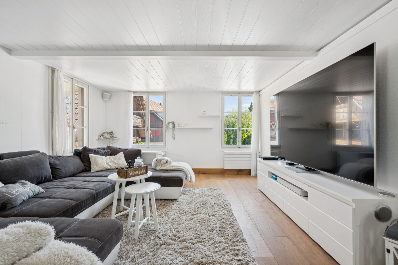 wohnzimmer mit natürliches licht, wood finish floor, holzfußboden, fernseher, und beamed ceiling