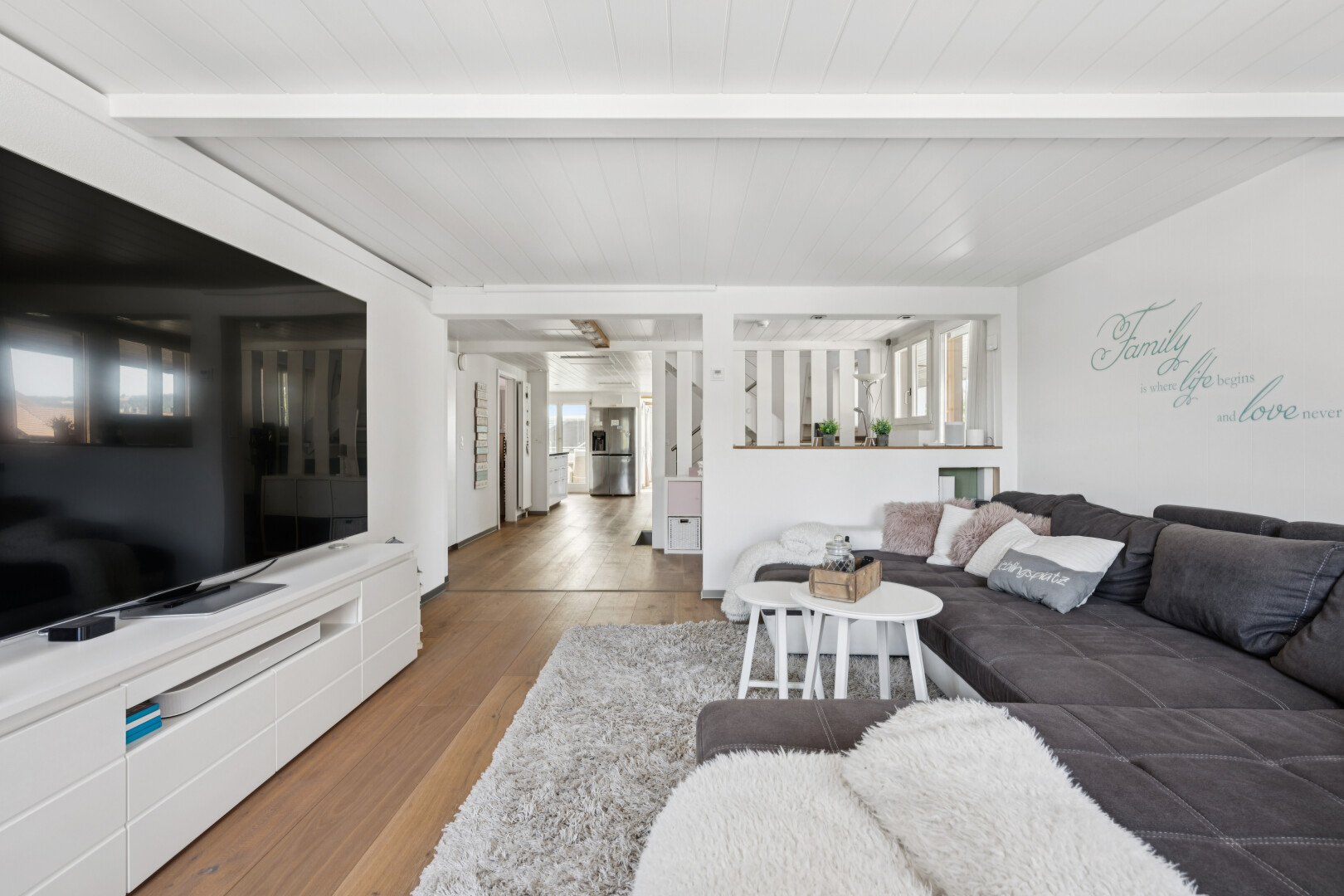 wohnzimmer mit fernseher, beamed ceiling, balkendecke, wood finish floor, und holzfußboden