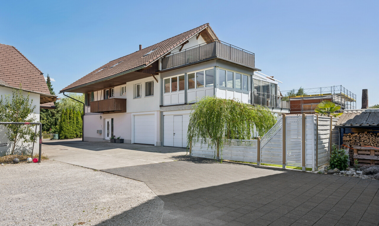 außenansicht mit auffahrt, eingebaute garage, day time, property visible, und stuckverkleidung