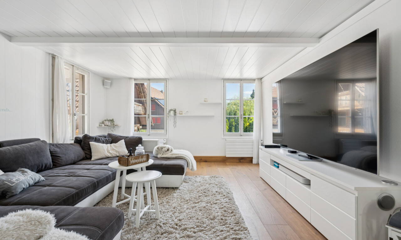 wohnzimmer mit natürliches licht, wood finish floor, holzfußboden, fernseher, und beamed ceiling