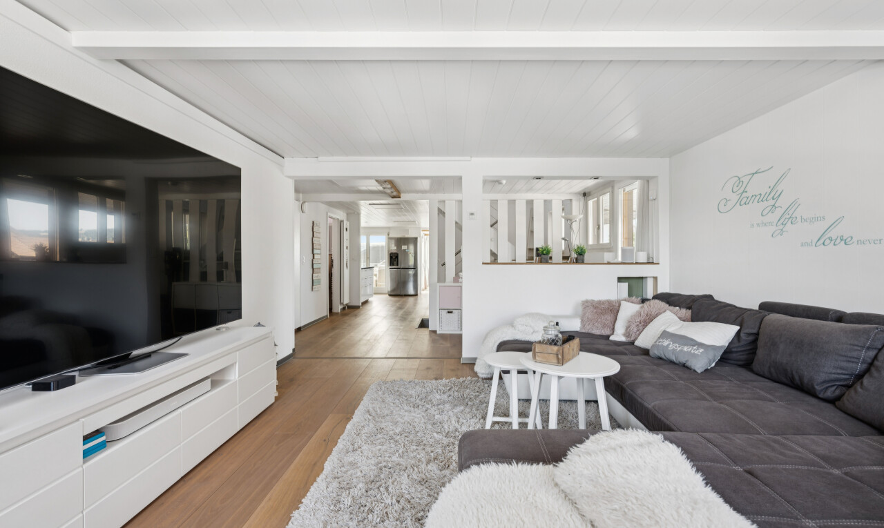 wohnzimmer mit fernseher, beamed ceiling, balkendecke, wood finish floor, und holzfußboden