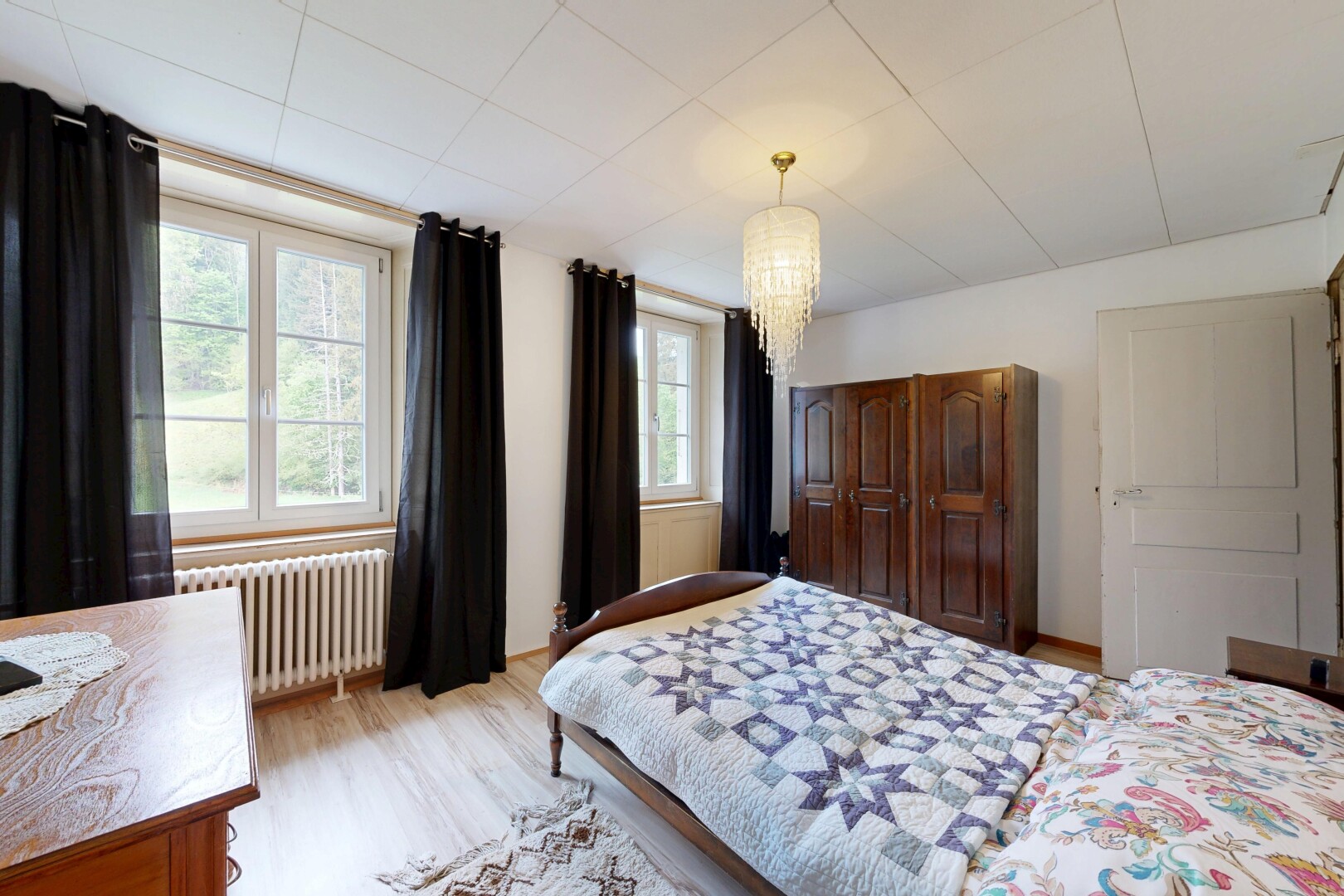 room featuring radiator heating unit, light wood finished floors, and suspended lighting