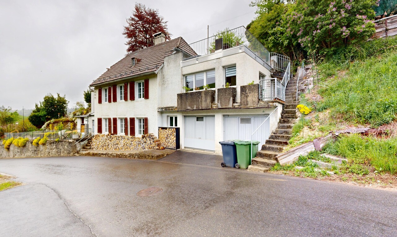 outdoor house with a chimney, stucco siding, driveway, an attached garage, and a balcony