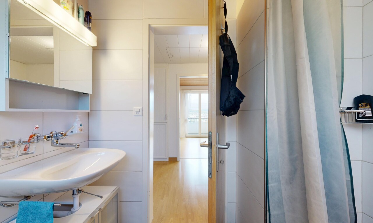 salle de bains avec miroir, évier, douche, inside property, et sol en finition bois